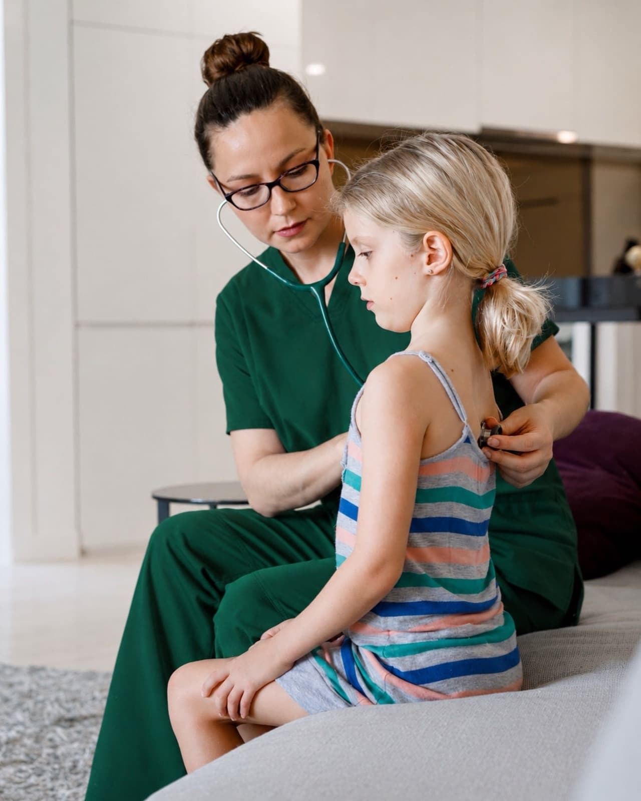 A nurse listening to a young girl's heartbeat with a stethoscope